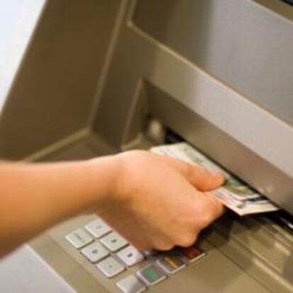 Un cliente retira dinero de un cajero de un banco