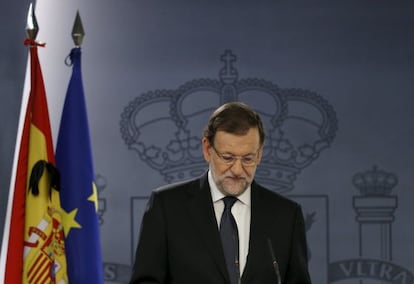 A black ribbon is seen on a Spanish flag as Prime Minister Mariano Rajoy speaks at La Moncloa.