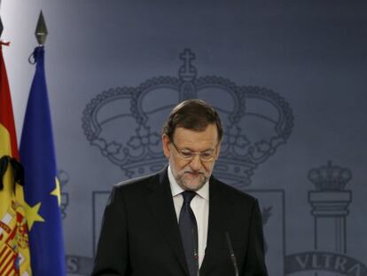 A black ribbon is seen on a Spanish flag as Prime Minister Mariano Rajoy speaks at La Moncloa.