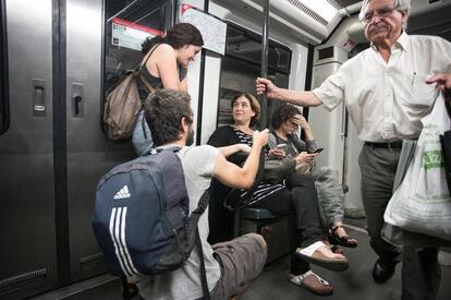 Ciutadans conversen i donen ànims a Ada Colau mentre ella treballa amb el mòbil a l'interior del metro.