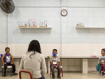 Una maestra da clase a tres de sus alumnos, todos separados por la distancia mínima de seguridad, en una escuela de educación primaria de São Paulo, en Brasil.