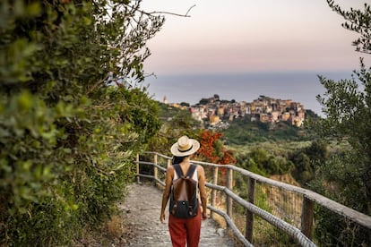 Una mujer atraviesa un sendero que conduce al pueblo de Corniglia (al fondo de la imagen).