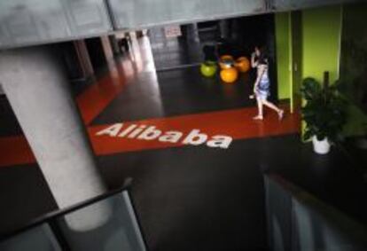 Una empleada pasa junto al logo de Alibaba en la sede de la empresa en Hangzhou (China). 