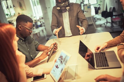 Directivo con gafas de realidad aumentada en una reunión con su equipo.