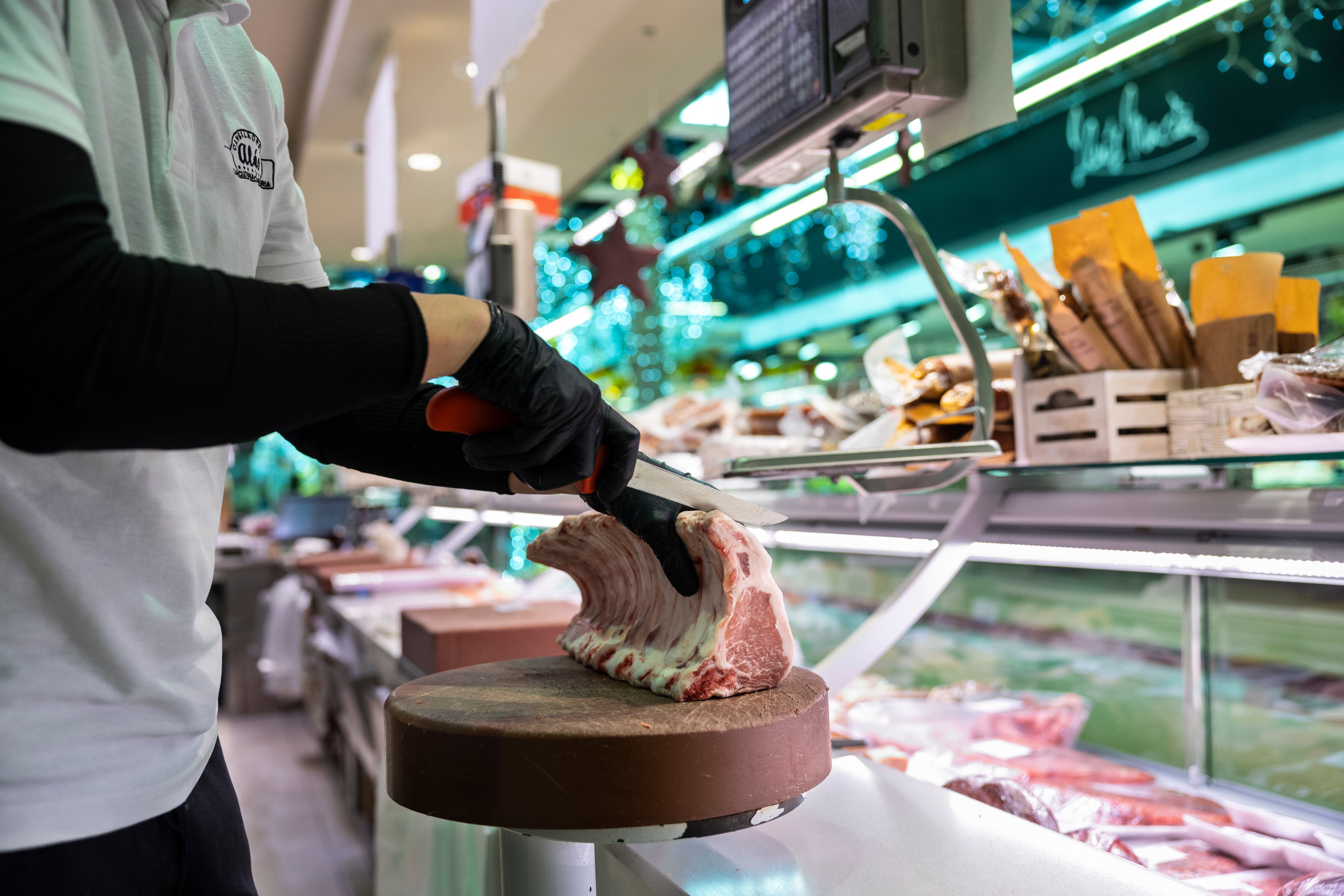 Un trabajador corta carne en una carnicería del Mercado del Ninot en Barcelona, el 2 de diciembre.