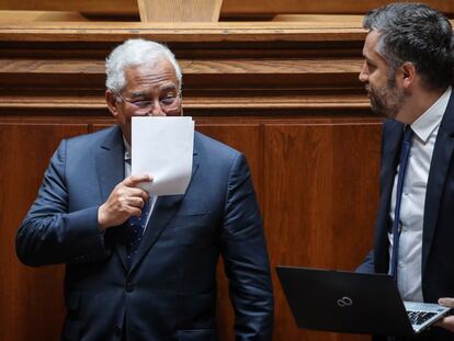 El primer ministro, António Costa, se tapa la cara mientras habla con el ministro de Infraestructuras, Nuno Santos, durante el debate para prorrogar el estado de emergencia en Portugal.