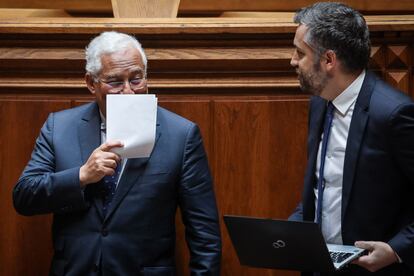 El primer ministro, António Costa, se tapa la cara mientras habla con el ministro de Infraestructuras, Nuno Santos, durante el debate para prorrogar el estado de emergencia en Portugal.