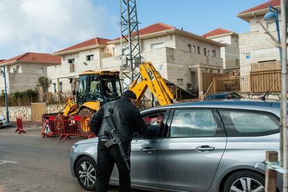 El vigilante armado Alex Izka controla el paso de un vehículo ante una obra con trabajadores palestinos en Ofra.