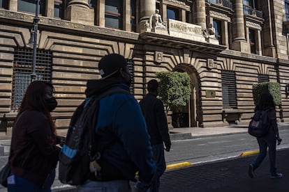 Un grupo de personas camina frente a la sede del Banco de México, en Ciudad de México.