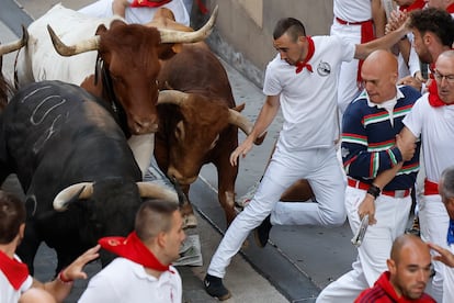 Un mozo cae ante los toros de la ganadería Jandilla durante el quinto encierro de los sanfermines, este viernes.