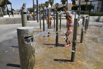 Varias niñas se refrescan en una plaza céntrica de Almería por el intenso calor.