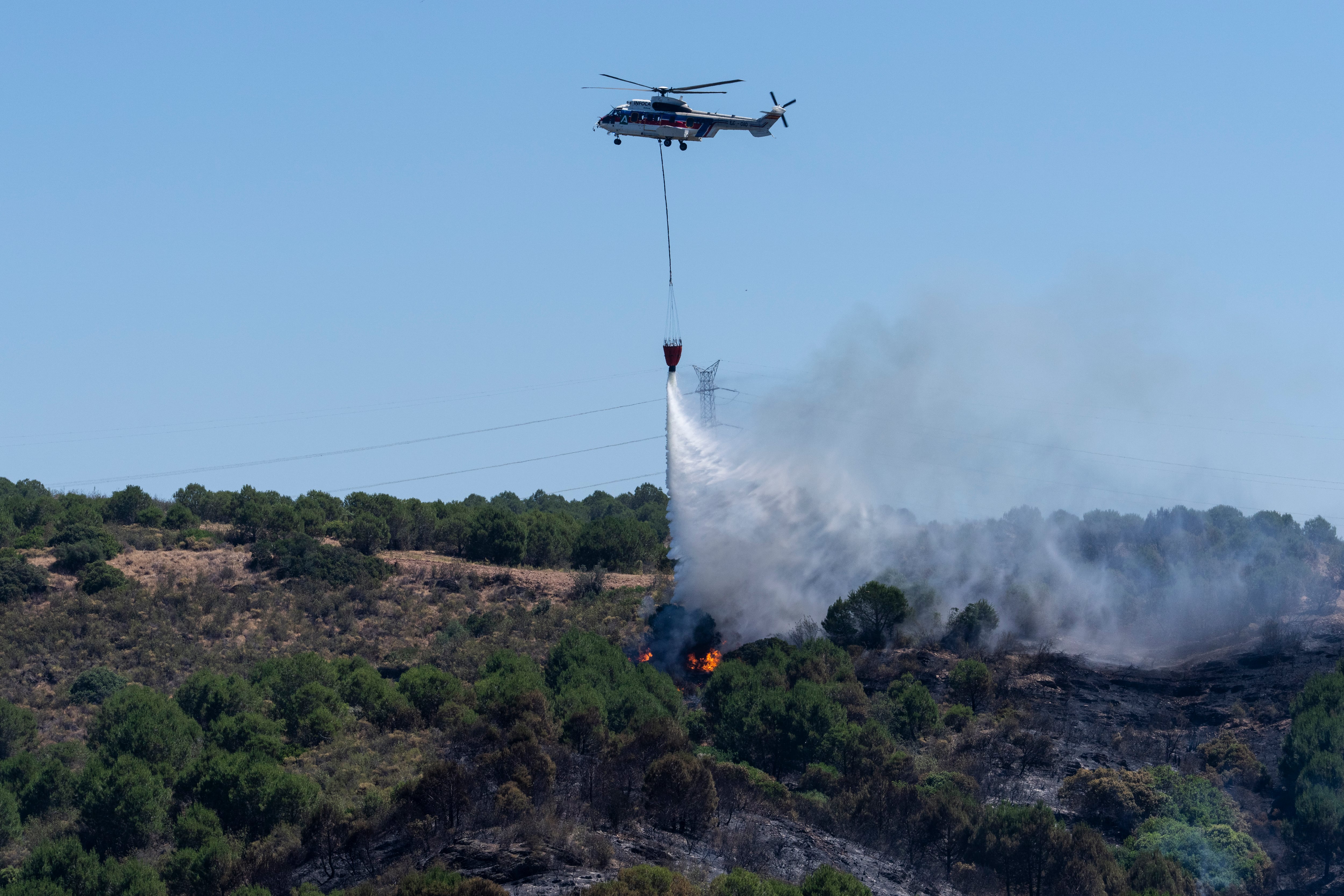 Un helicóptero trabaja en la extinción del incendio de Villanueva de los Castillejos (Huelva), este martes.
