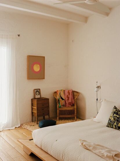 La cama de la habitación es un futón de Futon Company, y el flexo es el Tolomeo, de Artemide. Al fondo, un costurero antiguo sobre una alfombra marroquí. En la pared, un cuadro de Piers Jackson comprado en la galería Encant, en Mahón (Menorca).