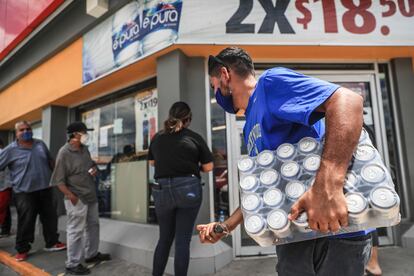 Un hombre con un paquete de cervezas afuera de un establecimiento comercial, en México.