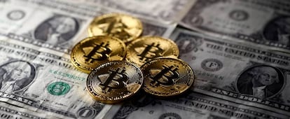 Monedas simuladas de Bitcoin sobre billetes de dólar.