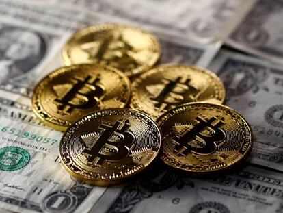 Monedas simuladas de Bitcoin sobre billetes de dólar.