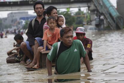 Un grupo de personas usan una balsa improvisada para cruzar una calle inundada en Yakarta, Indonesia. Las inundaciones causadas por las lluvias monzónicas han obligado a miles de personas a huir de sus hogares en la capital de Indonesia.