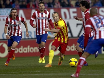 Iniesta conduce el balón rodeado de jugadores del Atlético 