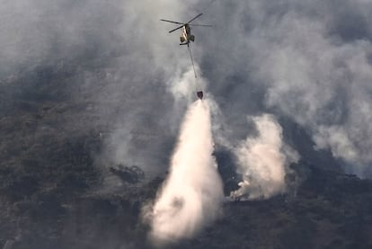 Un helicóptero trabaja este martes en las labores de extinción del incendio que desde ayer afecta a la Sierra de la Plata, en Tarifa (Cádiz).