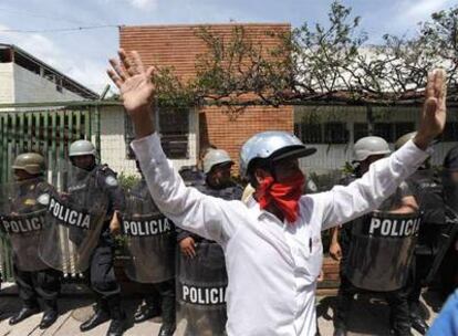 Un manifestante a favor del depuesto presidente Manuel Zelaya es rodeado por agentes policiales.