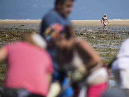 A bather and shellfish-catchers on the beach of Vilanova de Arousa (Pontevedra).