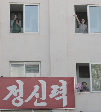 Vecinos de Pyonyang saludan desde la ventana al convoy que transporta a los líderes coreanos.