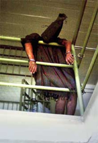Esta otra imágen muestra a un preso iraquí con un capuchón en la cabeza y esposado a una barrotes de la prisión de Abu Ghraib.