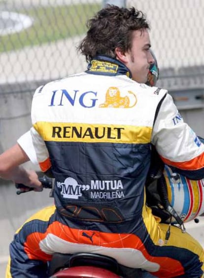 Fernando Alonso es recogido en motocicleta por un miembro de su equipo tras abandonar la carrera.