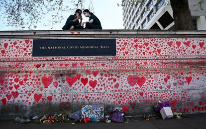 Dos enfermeras sentadas sobre el Muro Conmemorativo Nacional de Covid en Londres (Reino Unido). Algunos voluntarios han pintado corazones rojos en el muro en recuerdo a los que perdieron la vida a causa de la covid-19.