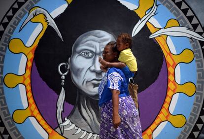 Una mujer de Papúa camina frente a un mural en el centro de Port Moresby, el 13 de noviembre de 2018, antes de la cumbre de Cooperación Económica Asia-Pacífico (APEC).