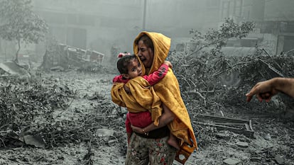 Una mujer huye con una niña en brazos minutos después de un bombardeo en Ciudad de Gaza, el 23 de octubre de 2023.