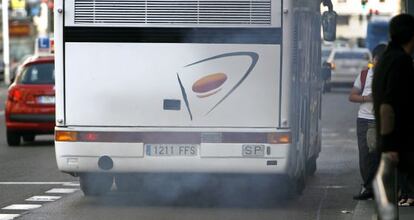 Un autocar expulsa gases por el tubo de escape circulando por el carril bus de la Gran Vía madrileña.