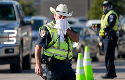 Police officer James Rhodes uses a wet towel to cool off as he directs traffic after a sporting event in Arlington, Texas, Saturday, Aug. 19, 2023.