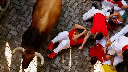Un astado de la ganadería Fuente Ymbro pasa junto a un grupo de corredores, este miércoles en Pamplona.