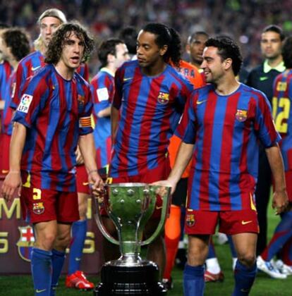 Puyol, Ronaldinho y Xavi sujetan el trofeo de la Liga.
