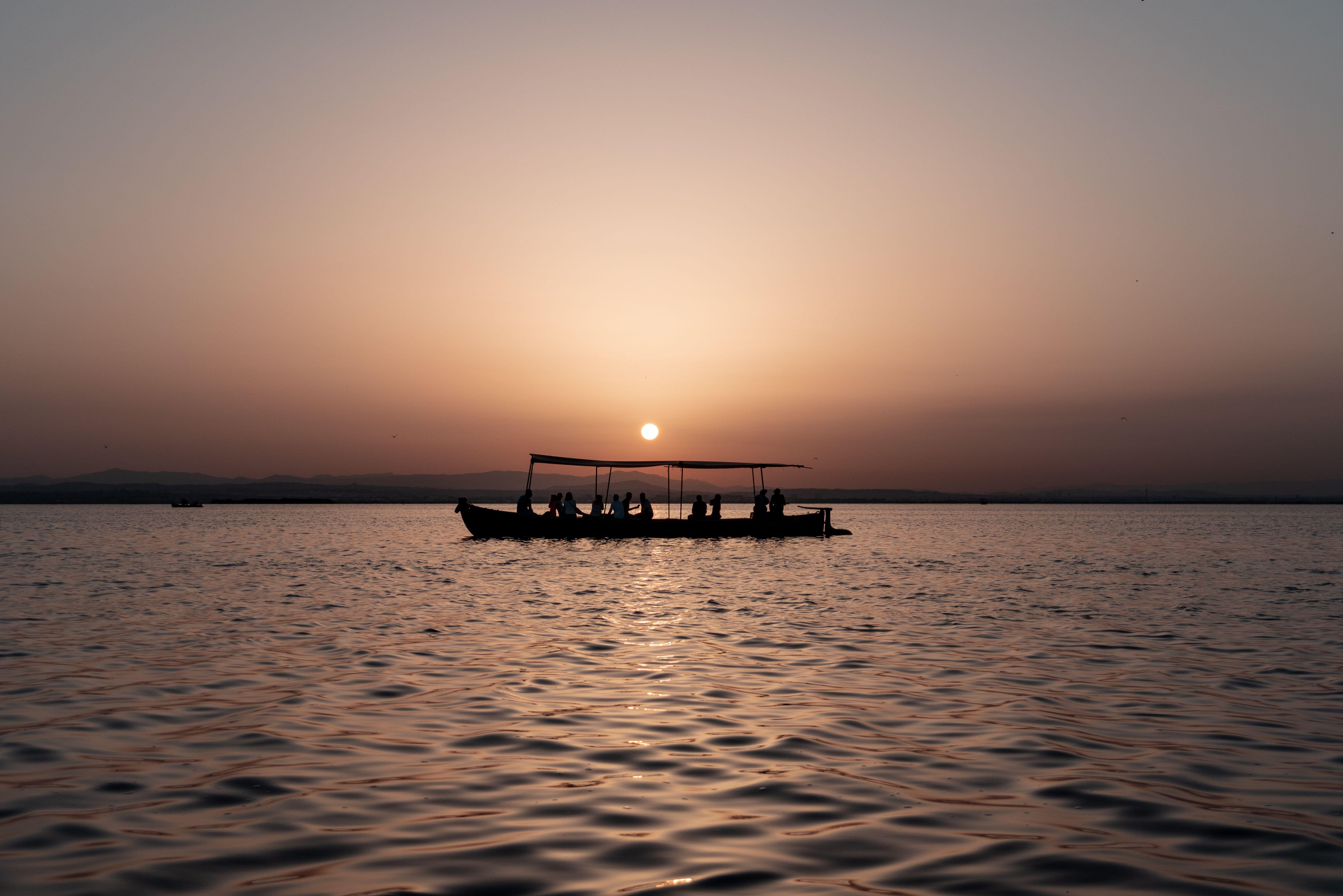 Una barca navegando por aguas de la Albufera al atardecer.