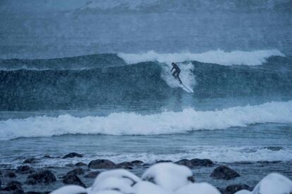 Um surfista pega onda sob uma tempestade de neve em Unstad, Ilhas Lofoten.