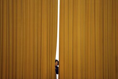 Un miembro del staff se asoma por una cortina antes de una rueda de prensa, tras la Asamblea anual del Parlamento chino en el Gran Salón del Pueblo de Pekín (China).