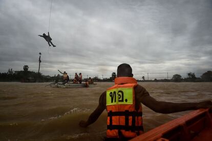 Un soldado baja de un helicóptero para distribuir suministros a un bote de rescate, en el distrito Chaiya (Tailandia).
