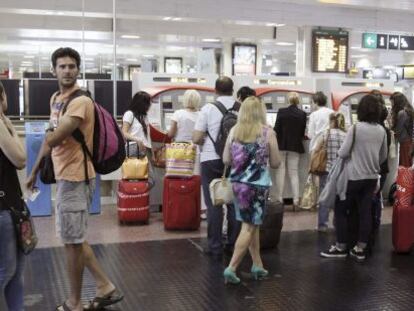 Varias personas hacen cola para comprar un billete de tren en las m&aacute;quinas expendedoras, en la estaci&oacute;n de Chamart&iacute;n, en Madrid.