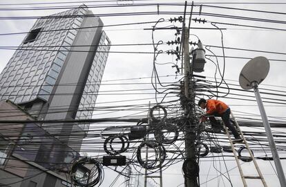 Un trabajador retira algunos cables de electricidad de una calle de Bangkok (Tailandia). El gobierno tailandés aprobó en 2016 un presupuesto para hacer subterráneos los cables de electricidad de la ciudad de Bangkok, con la intención de prevenir accidentes y mejorar la aparicencia de la ciudad.