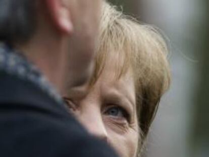 Angela Merkel mira a Juncker en una visita del presidente del Eurogrupo a Alemania.