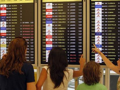 Varios pasajeros consultan un panel de informaci&oacute;n en Barajas.