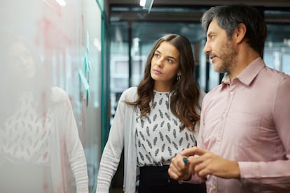 Coworkers discussing over whiteboard in office