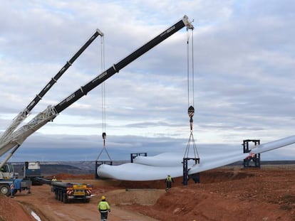 Las grúas levantan la pala de una turbina eólica cerca del pequeño pueblo soriano de Beltejar.