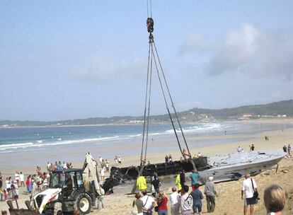 Una grúa retira la planeadora abandonada en una playa de O Grove.