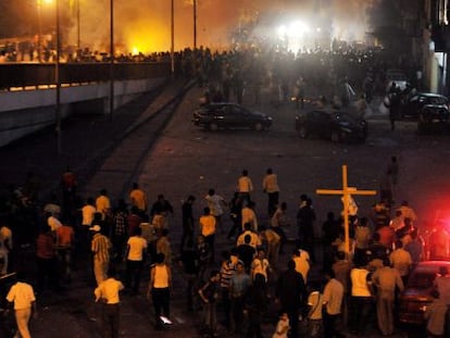 Cristianos coptos (abajo) se enfrentan a fuerzas de seguridad egipcias (arriba) mientras una multitud corre en un puente durante protestas llevadas a cabo frente al edificio de la radiotelevisi&oacute;n en El Cairo.