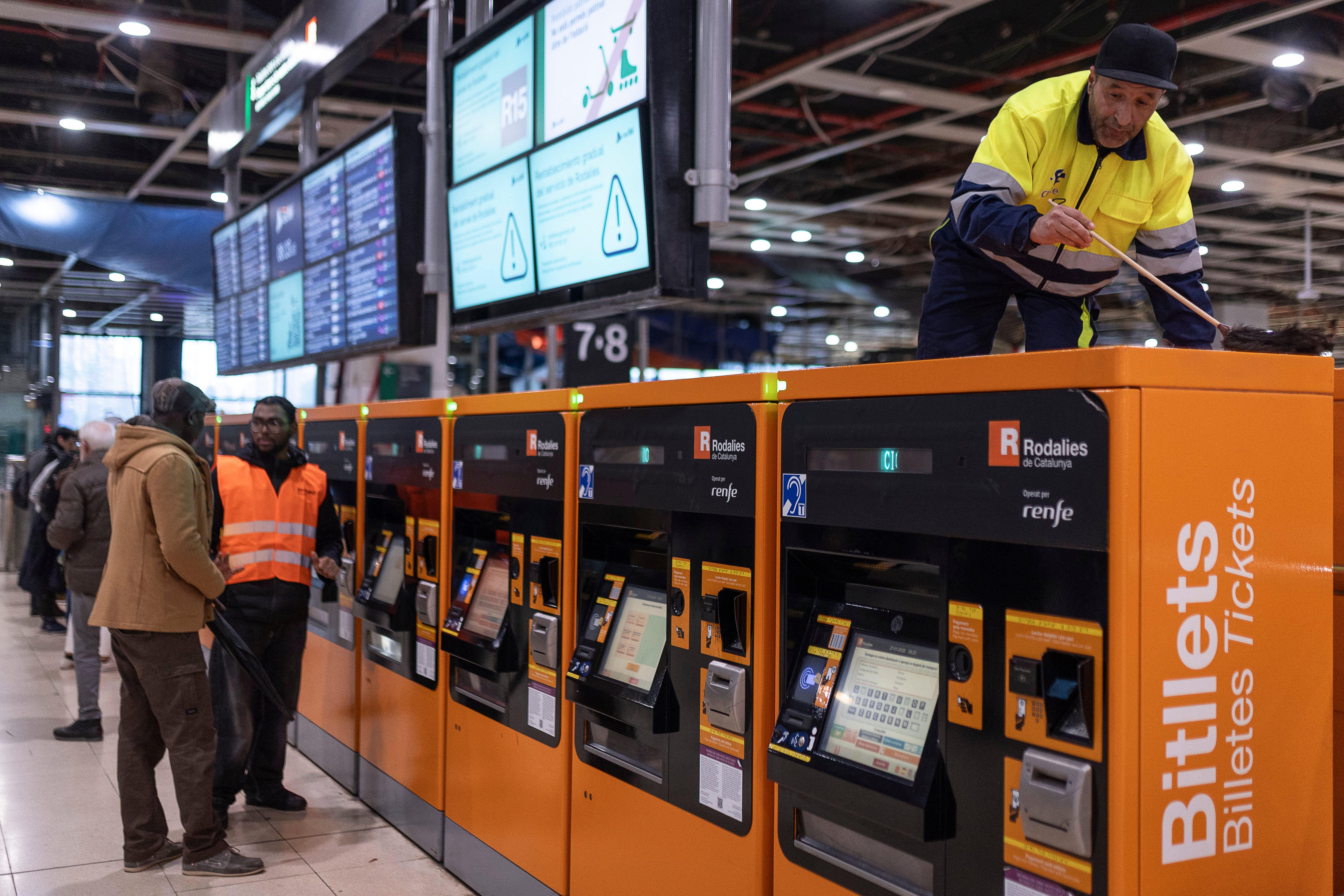 La vuelta la teórica vuelta a la normalidad, este jueves a primera hora, representada por un empleado sacando el polvo a las máquinas expendedoras de Sants.