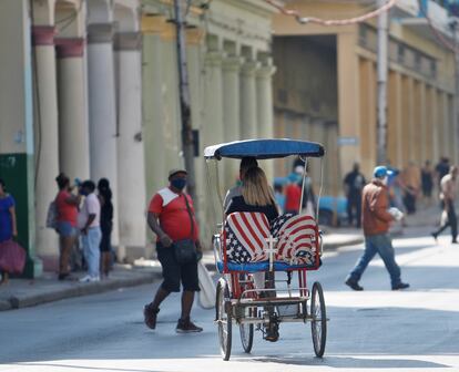 Un bicitaxi con los asientos tapizados con la bandera estadounidense transitando por La Habana (Cuba).