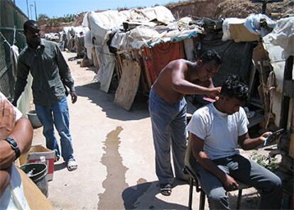 Varios inmigrantes, fotografiados ayer en las chabolas situadas junto al refugio de Melilla donde se hacinan los extranjeros que no tienen plaza.